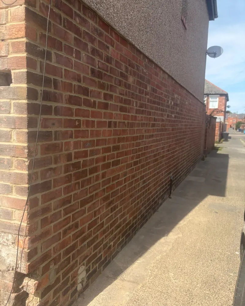 The same gable wall after repointing, with neat, even joints
