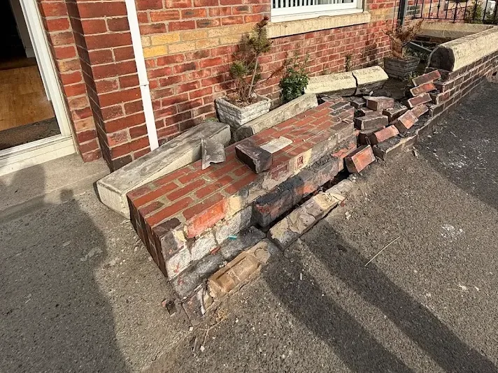 Collapsed brick front garden wall before repair